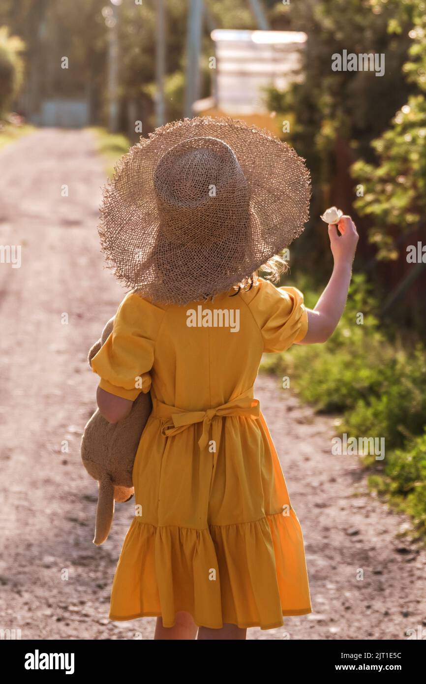 cute little girl in a yellow dress and straw hat walking Stock Photo ...