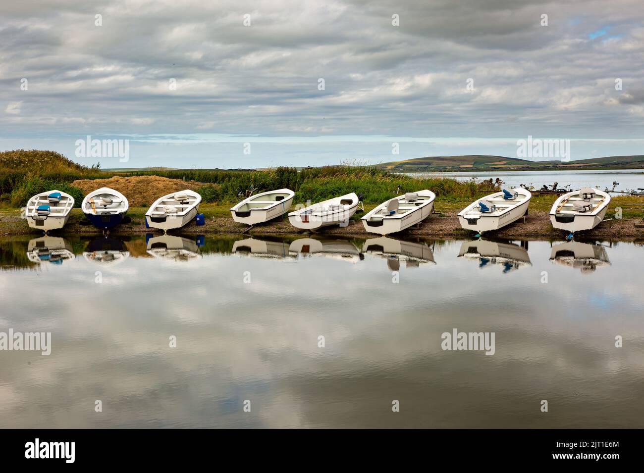 Loch Harray, Orkney, UK. 27th Aug, 2022. Dinghies are reflected in the calm waters of Loch Harray, Orkney mainland, UK. The boats are used by local fly fishing enthusiasts. Credit: Peter Lopeman/Alamy Live News Stock Photo