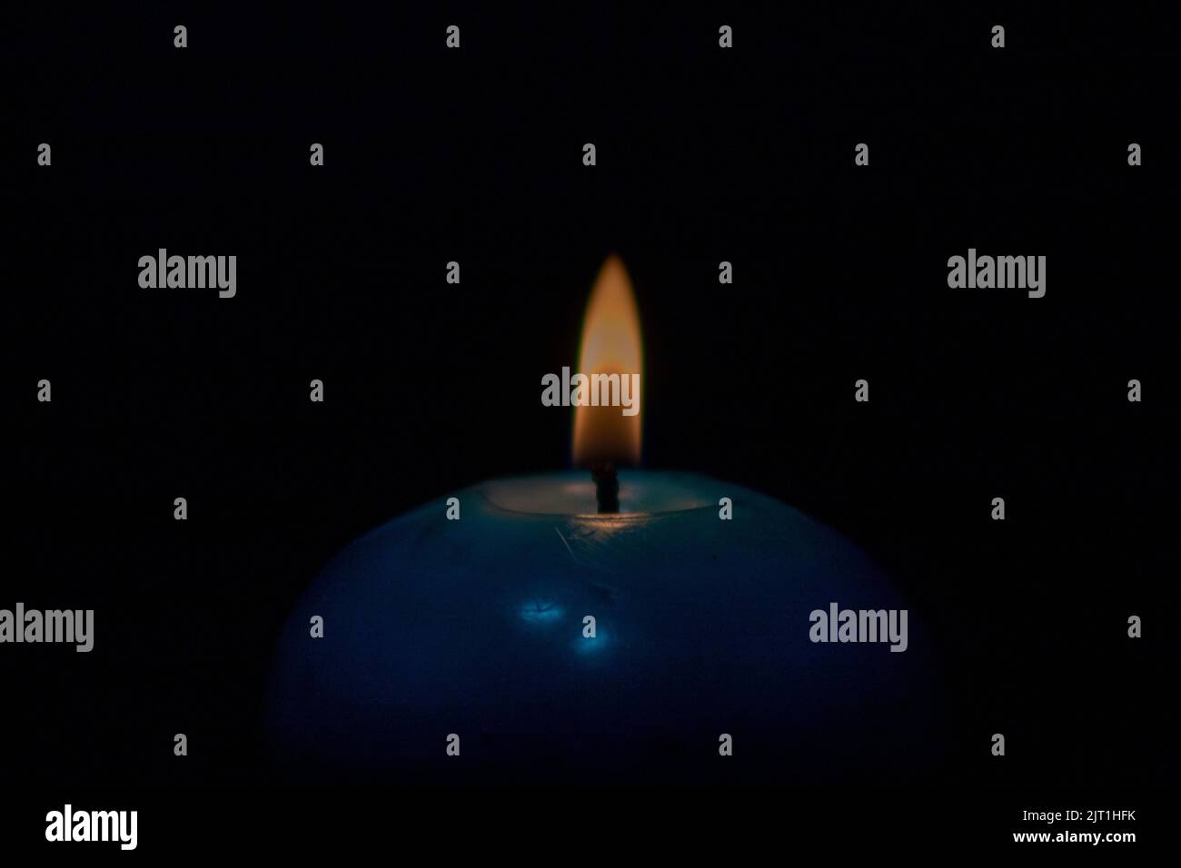 Candle flame and a blue candle on isolated black background Stock Photo