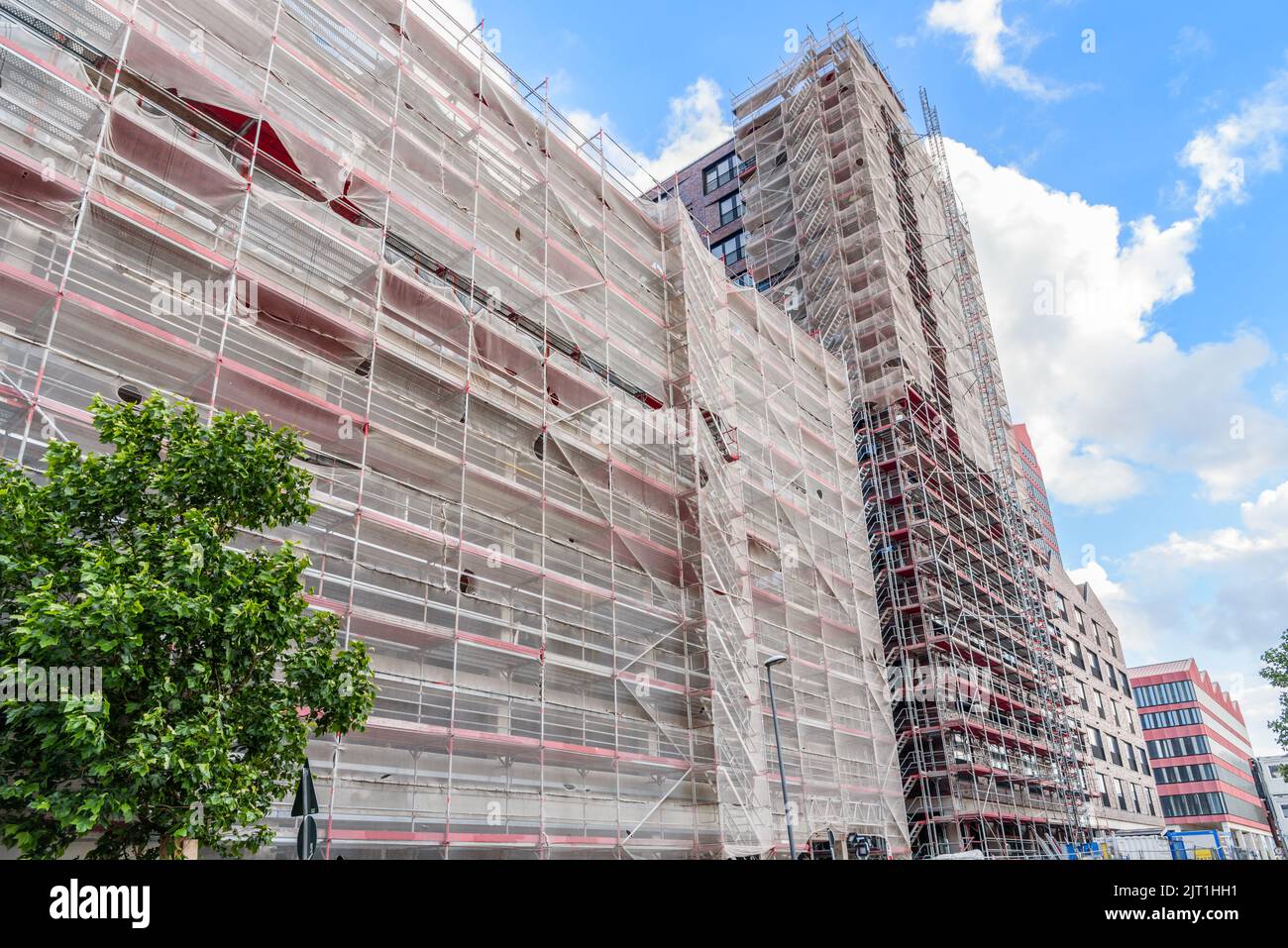 Low angle view of a high rise building in construction wrapped with scaffolding in a city centre on a clear summer day Stock Photo