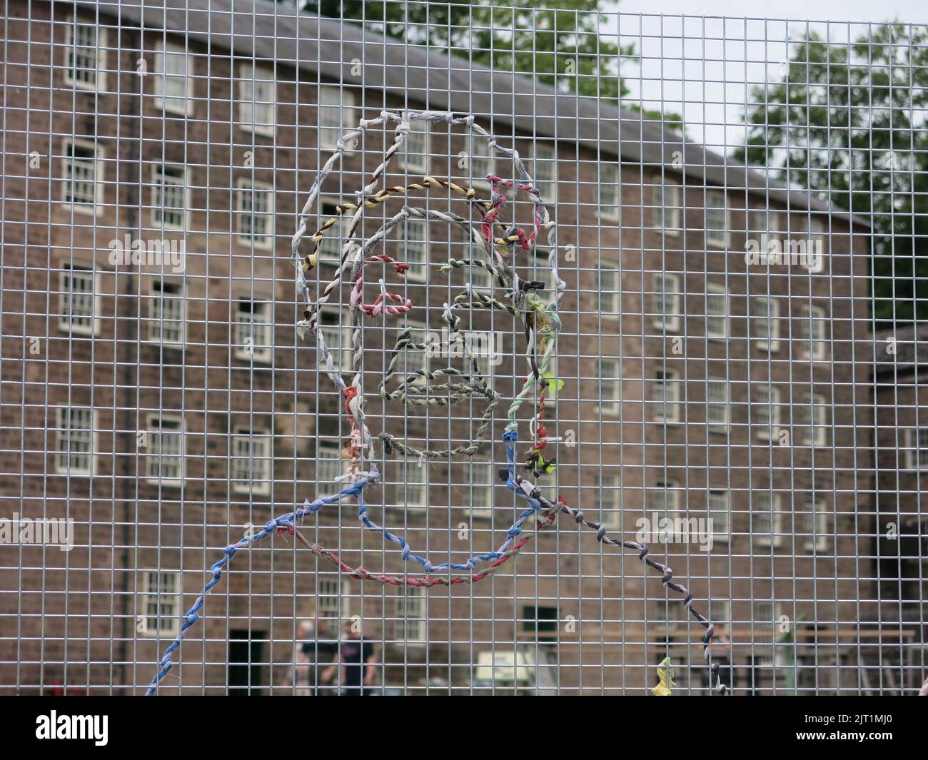 'Cotton Labour': art installation by Hetain Patel, symbolic portraits woven with yarn into a mesh structure against a backdrop of Cromford Mills. Stock Photo