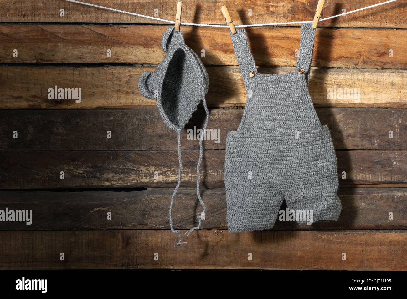 baby clothes, hung on a clothesline with wooden hooks, overalls and hat. clothes are drying in