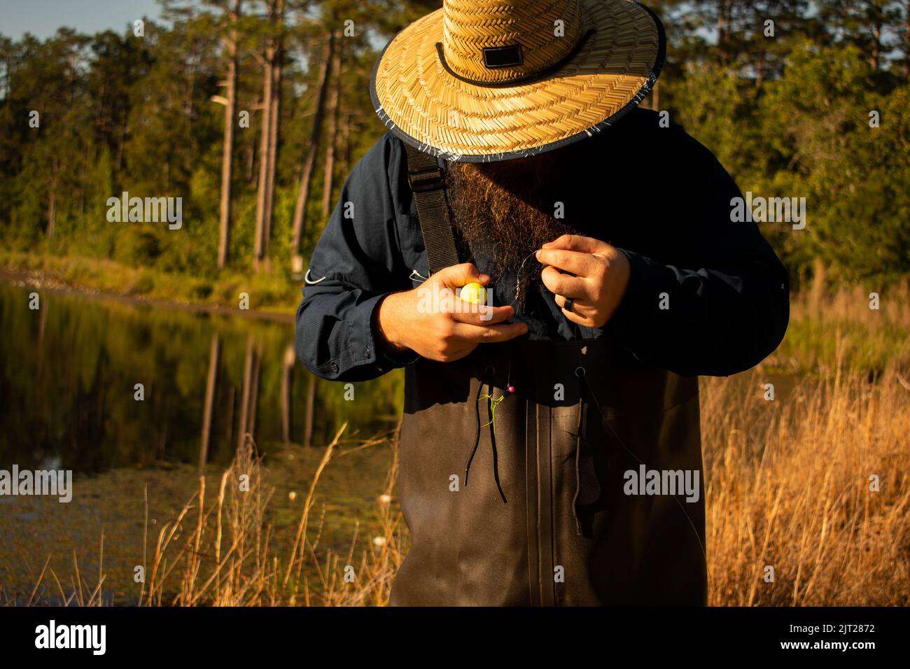 Fisherman in waders detangling line for fly fishing at lake Stock Photo
