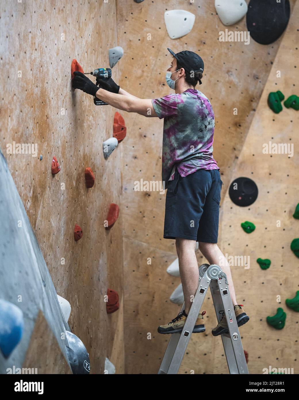 A climbing route setter trying to set a route in the bouldering gym