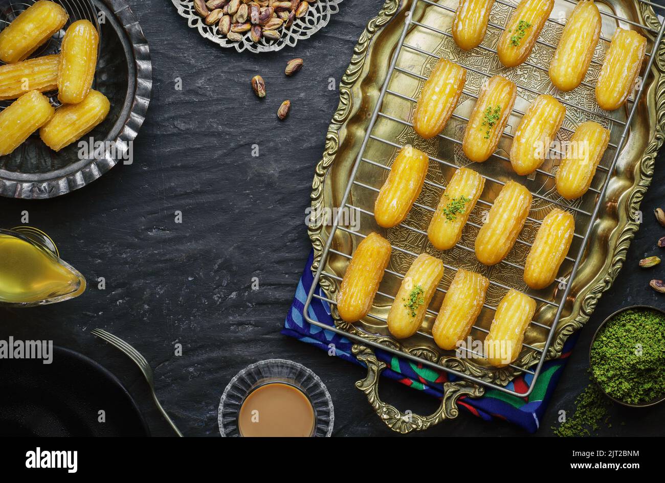 Arabic Cuisine: Middle Eastern Traditional dessert/Ramadan dessert Balah Al-Sham or Balah El Shaam served with pistachio and  honey syrup. Stock Photo