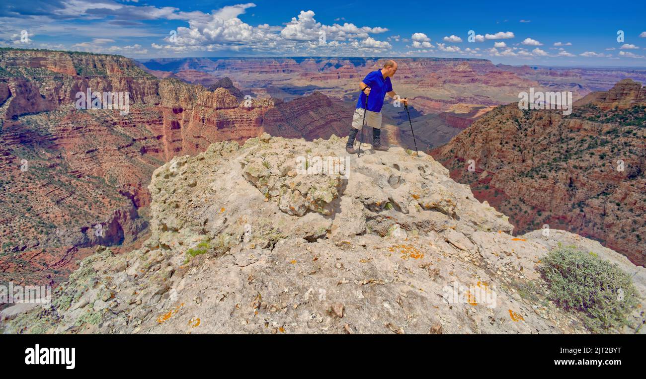 A hiker on the edge of a cliff along Buggeln Hill Trail halfway between Grandview Point and the Sinking Ship at Grand Canyon Arizona. Stock Photo