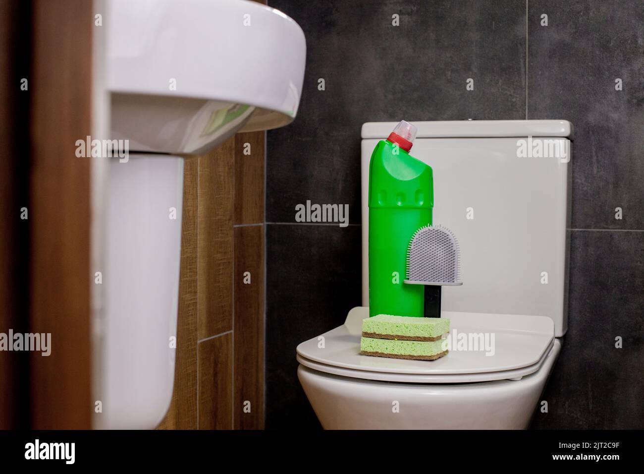 Toilet cleaner, a toilet brush and a washcloth on the toilet. Toilet