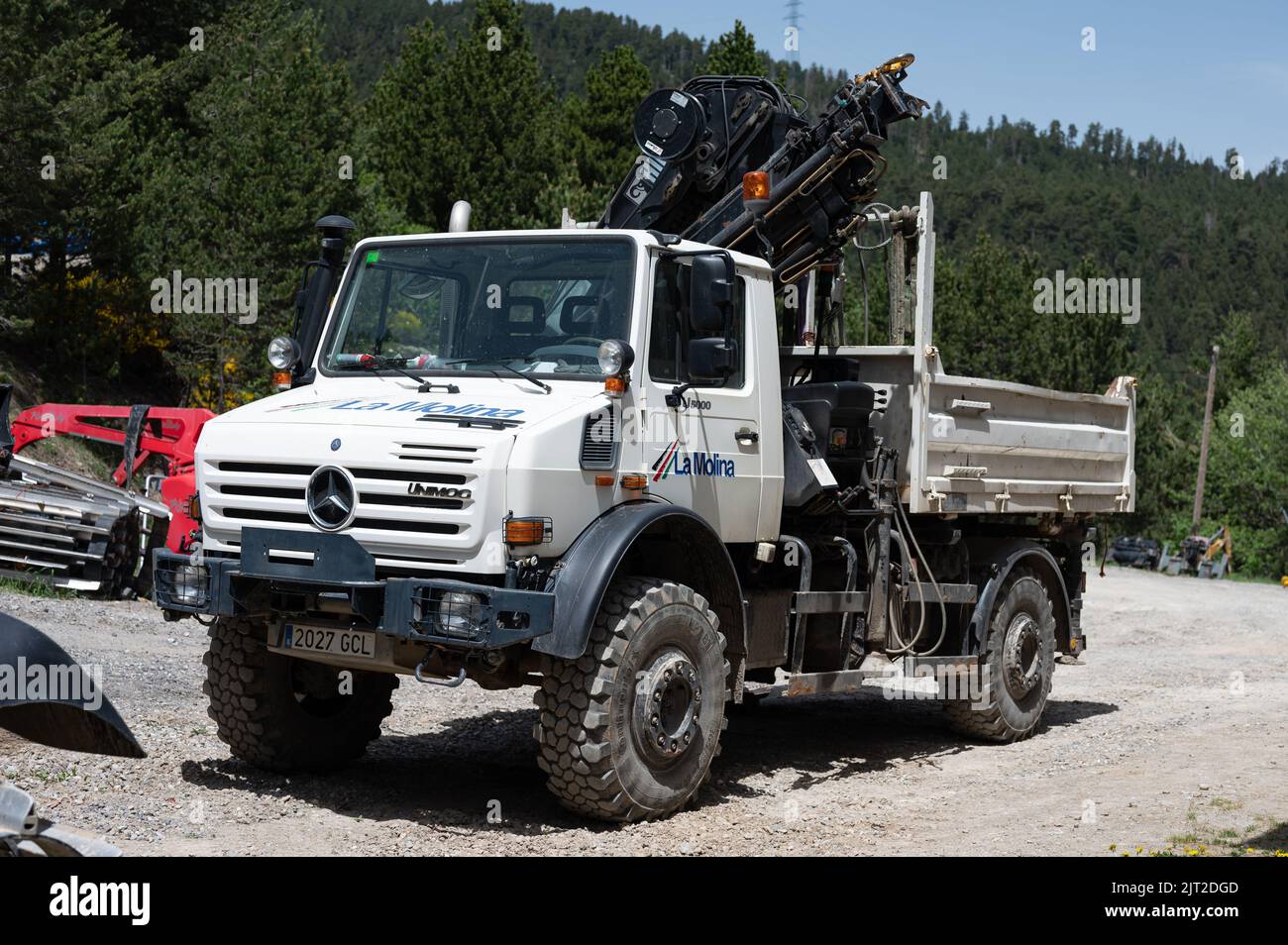 A white Mercedes Benz Unimog G5000 off-road truck with a crane parked on a construction site Stock Photo