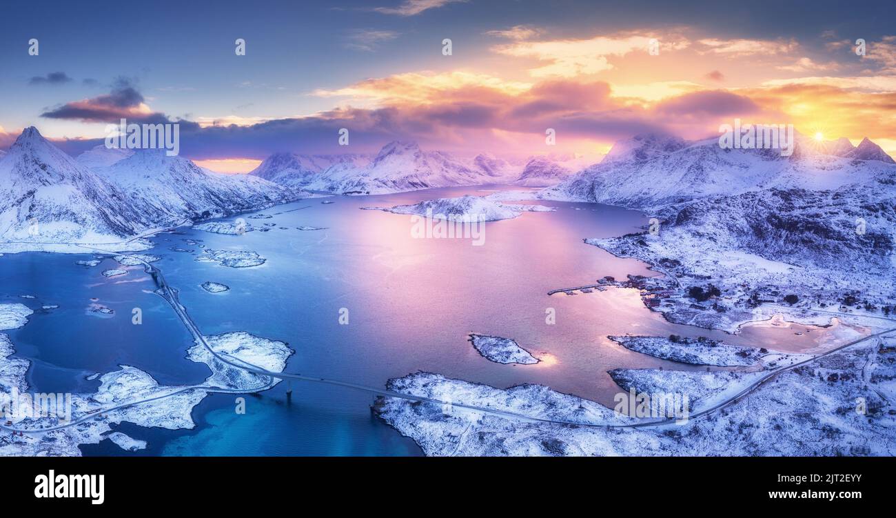 Aerial view of blue sea, snowy mountains, sky with pink clouds Stock Photo