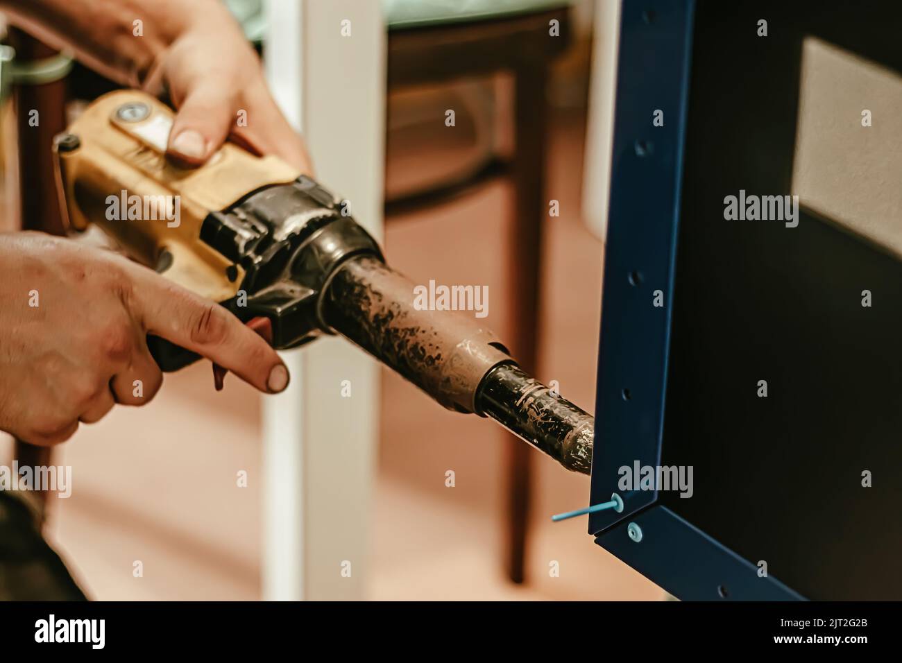 Male worker uses electric riveting gun. Hand holding riveting machine