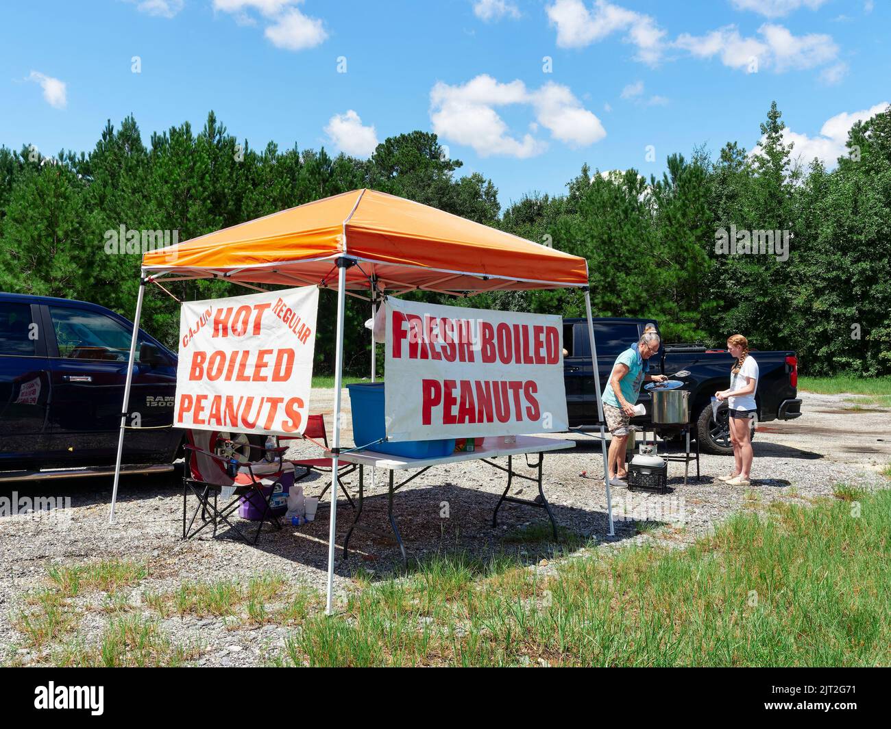 Woman and girl selling from a fresh hot boiled peanut stand, to a customer as a roadside business in Montgomery Alabama, USA. Stock Photo