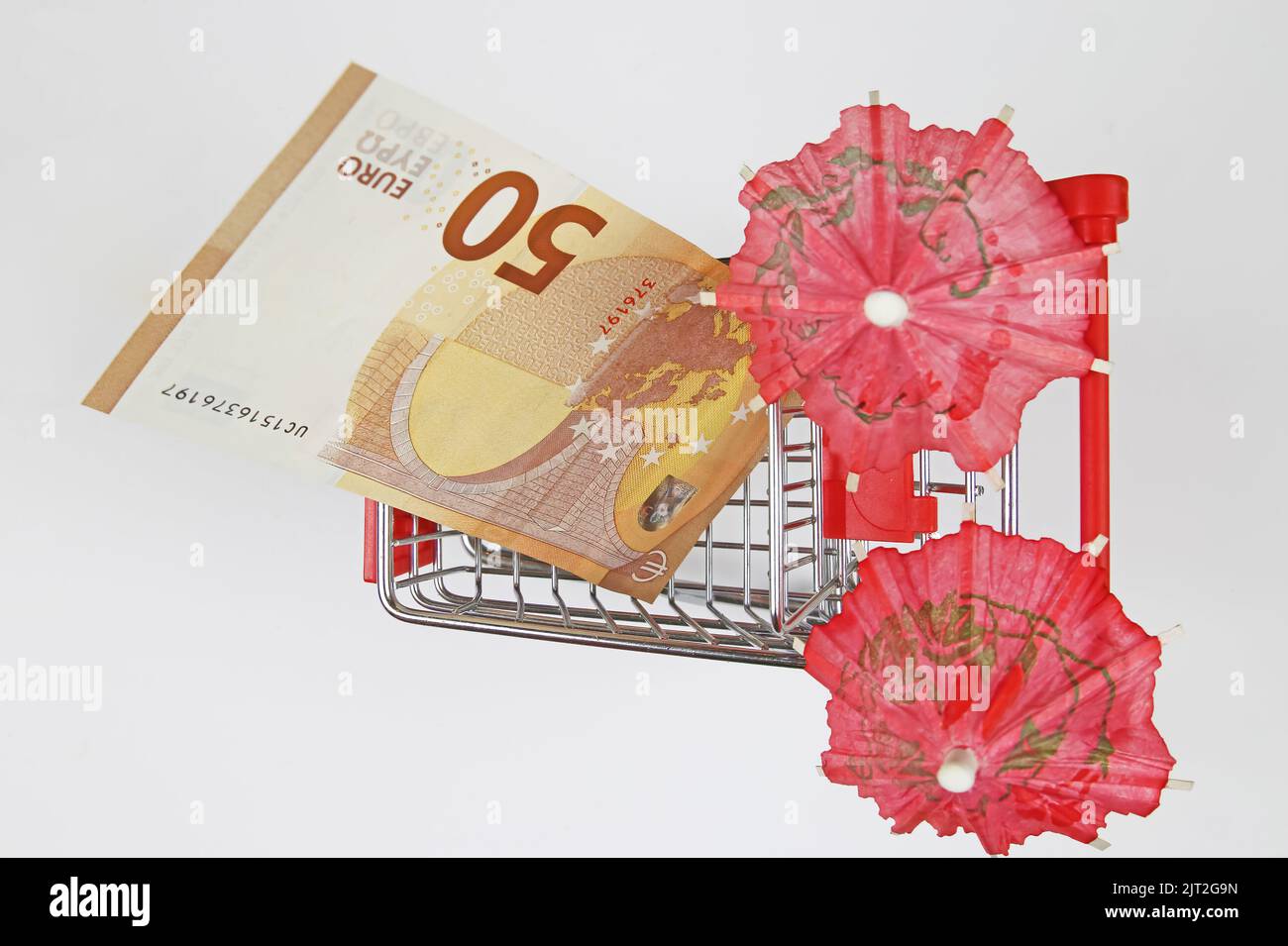 Top view on isolated shopping cart model with 50 Euro banknote, two umbrellas, white background Stock Photo