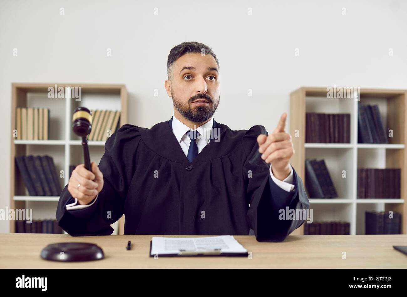 Portrait of stern judge knocking on judge's gavel passes sentence and declares case closed. Stock Photo