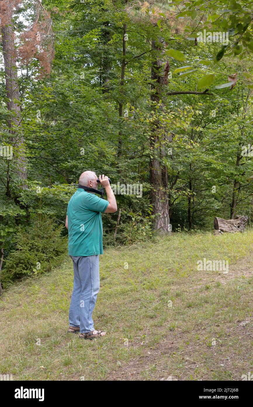 sideview of a man watching nature with binoculars Stock Photo