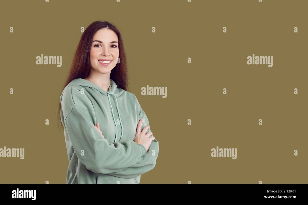 Happy young woman in casual clothes standing with her arms crossed on copy space background Stock Photo
