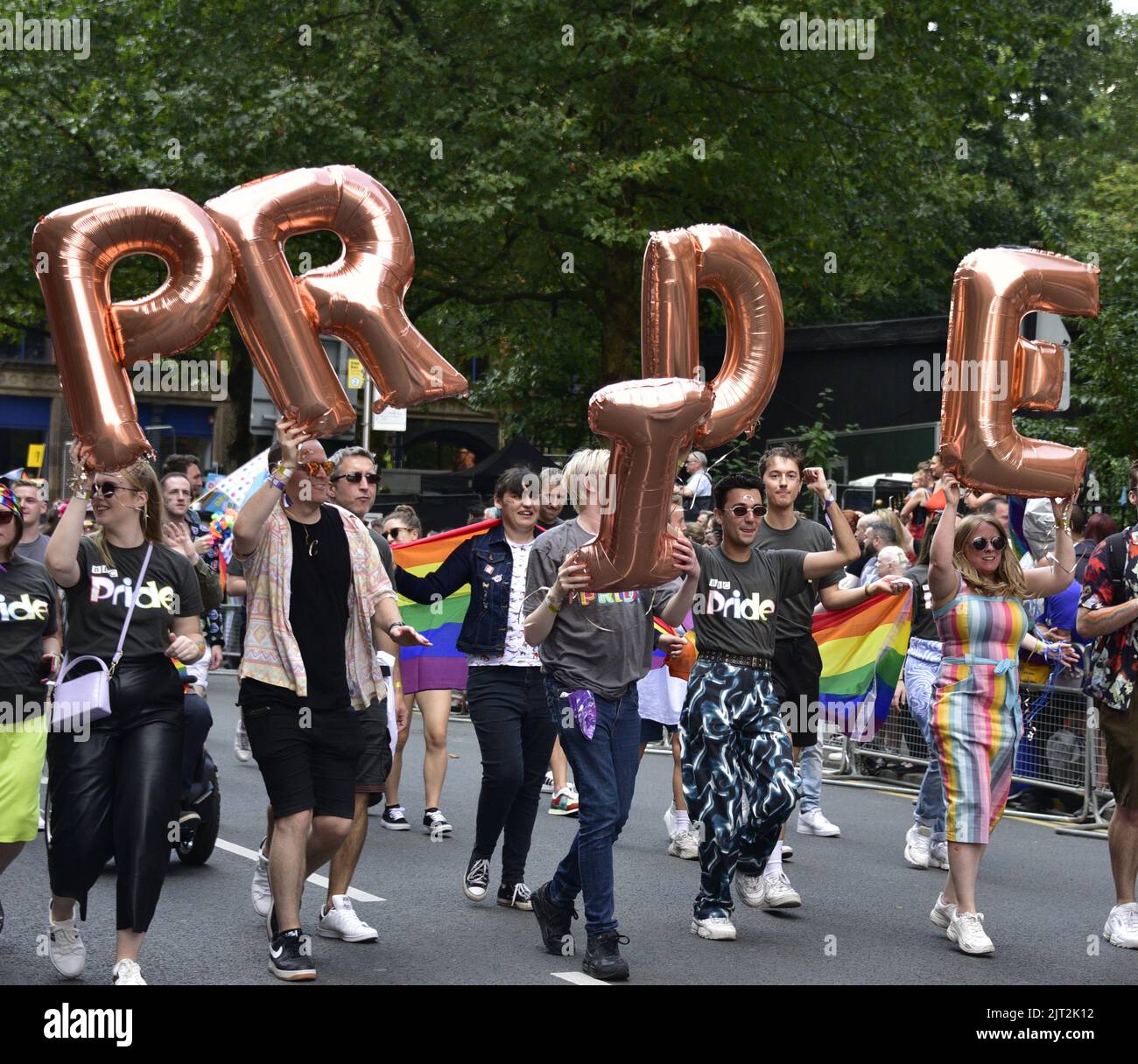 Manchester, UK. 27th August, 2022. A group carry inflatable letters to spell 'Pride'. Participants take part in the LGBTQ+ Pride parade, central Manchester, UK, as LGBTQ+ Pride continues over the Bank Holiday weekend 26th to 29th August. Organisers say: 'Manchester Pride is one of the UK's leading LGBTQ+ charities. Our vision is a world where LGBTQ+ people are free to live and love without prejudice. We’re part of a global Pride movement celebrating LGBTQ+ equality and challenging discrimination.' Credit: Terry Waller/Alamy Live News Stock Photo