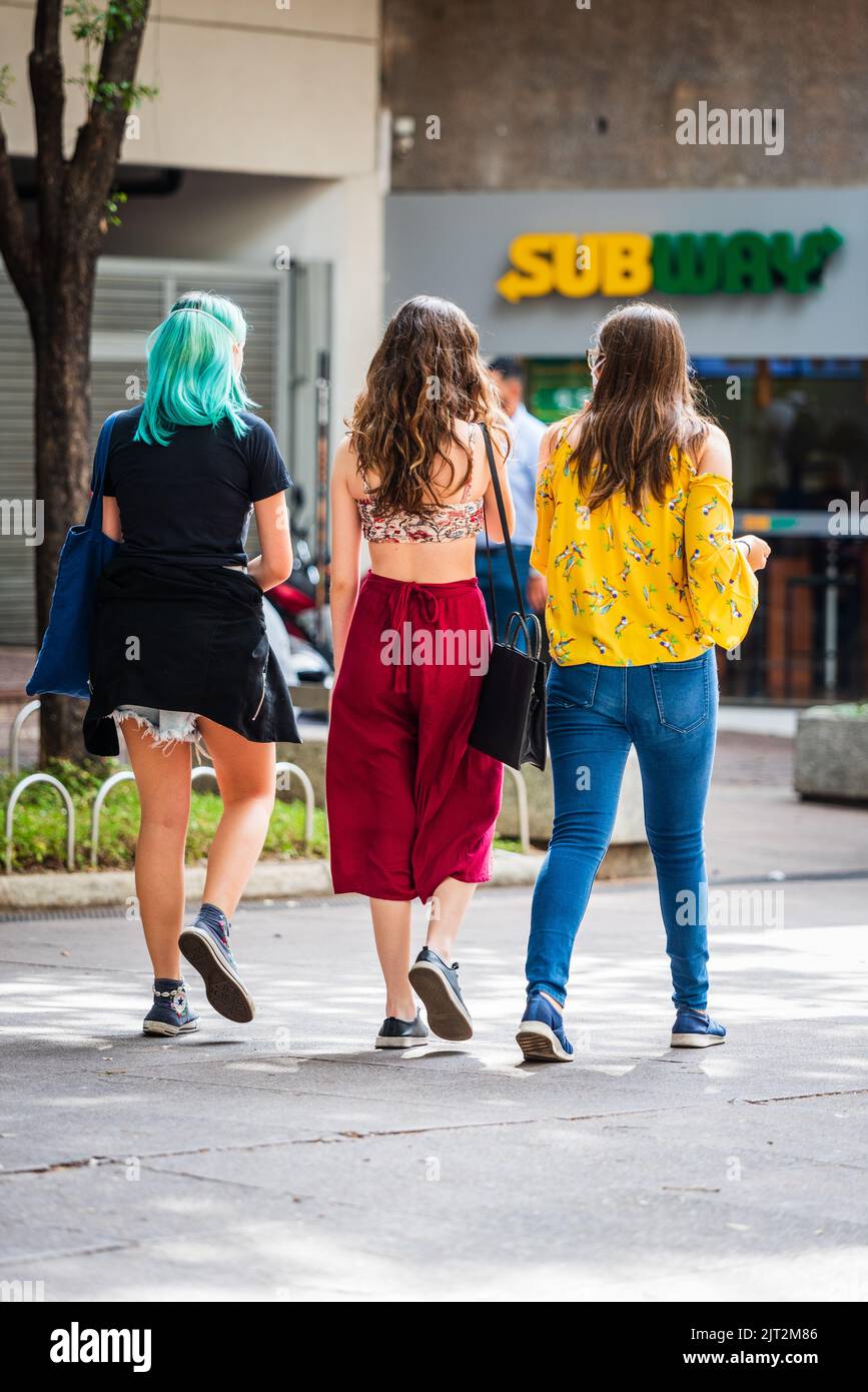 Back view of three Brazilian young women waking towards a Subway restaurant at Savassi, in Belo Horizonte, Brazil. Stock Photo