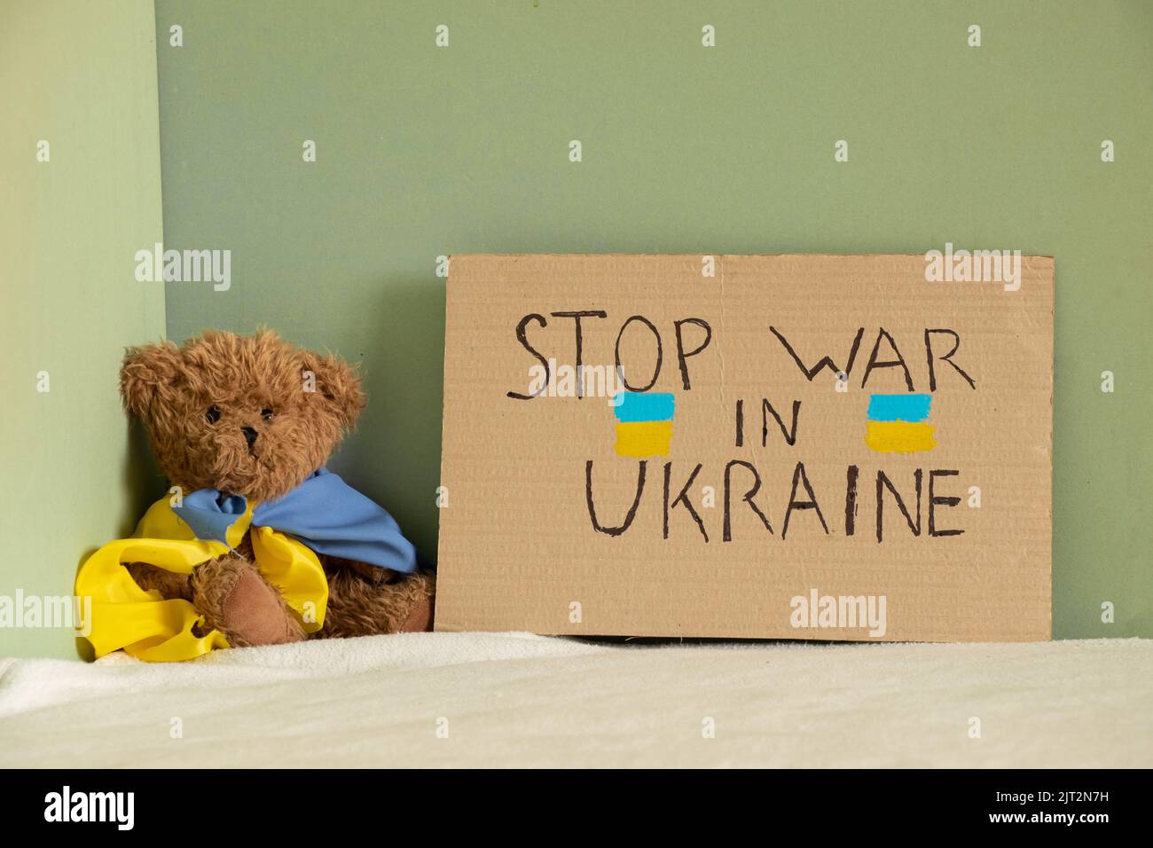 Stop the war in Ukraine, written on a sign that stands on the bed of a house in Ukraine next to a teddy bear. Peace in Ukraine. Protest 2022 Stock Photo