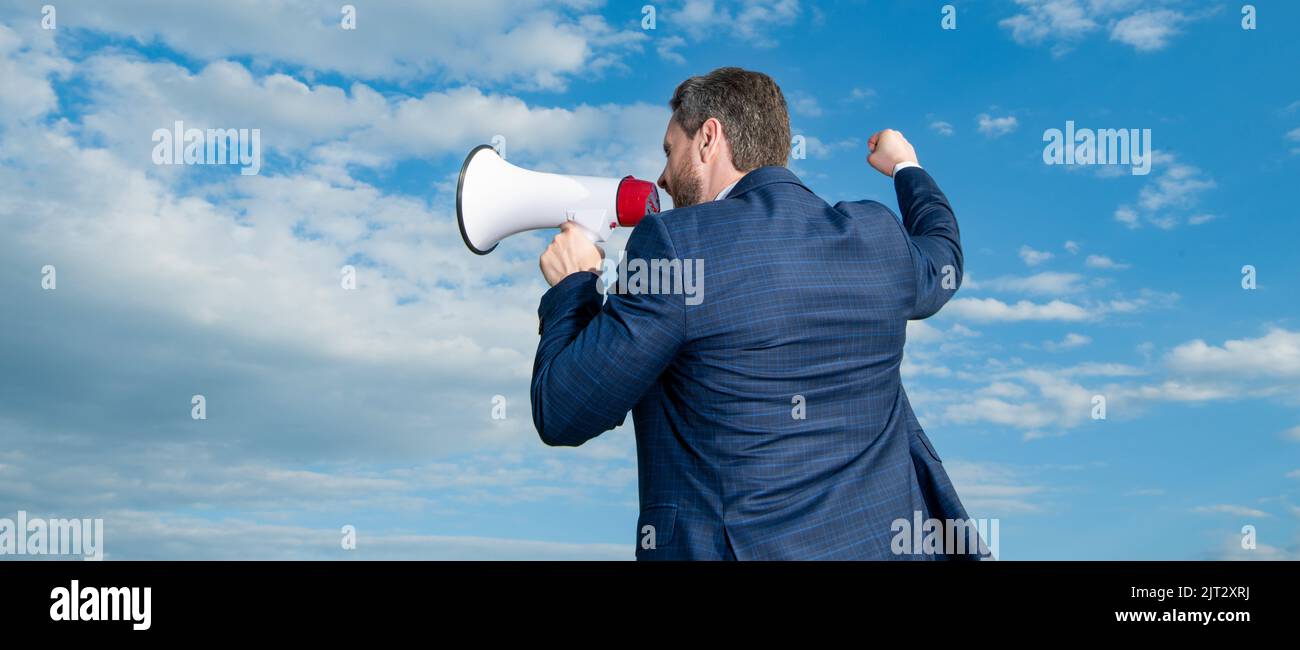 back view of businessman shout in loudspeaker on sky background ...