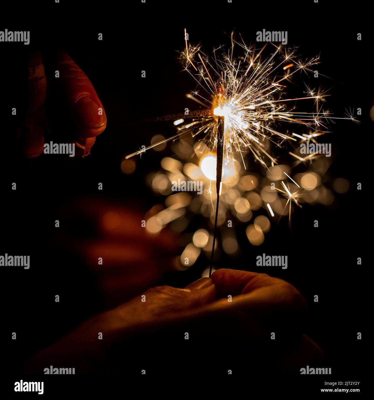 A sparkler being held at a party, with a shallow depth of field Stock Photo