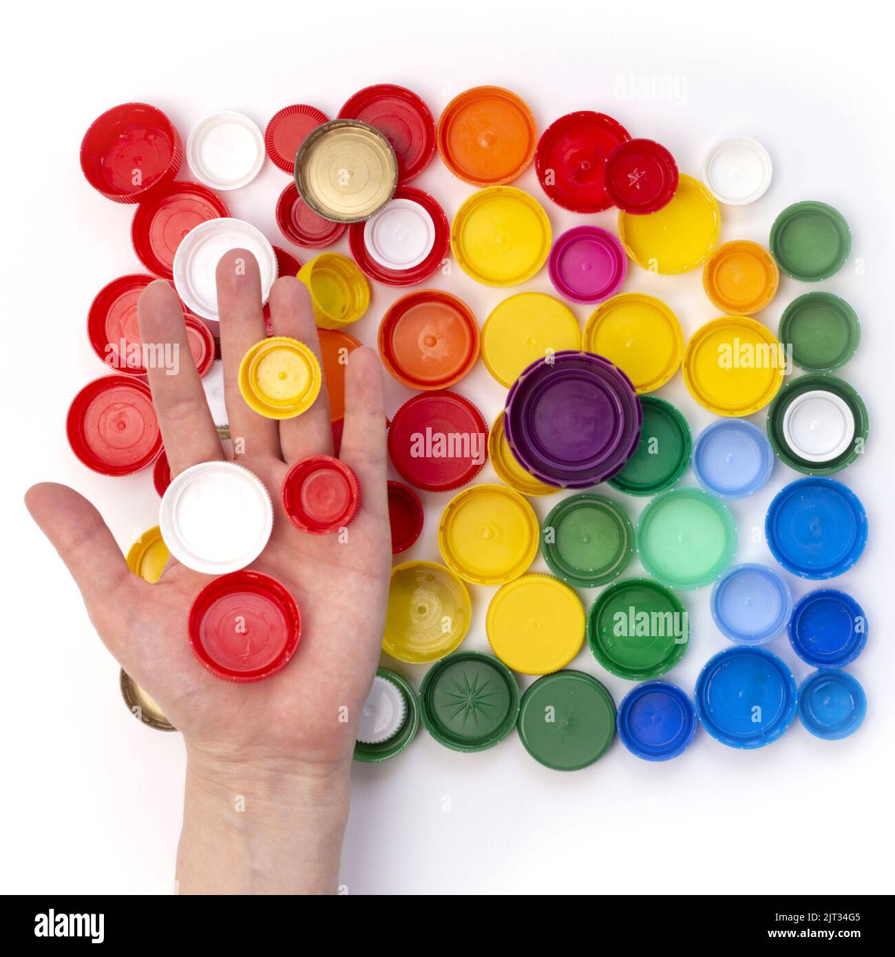 hand holds plastic bottle lid, rainbow color pattern, remove cap before