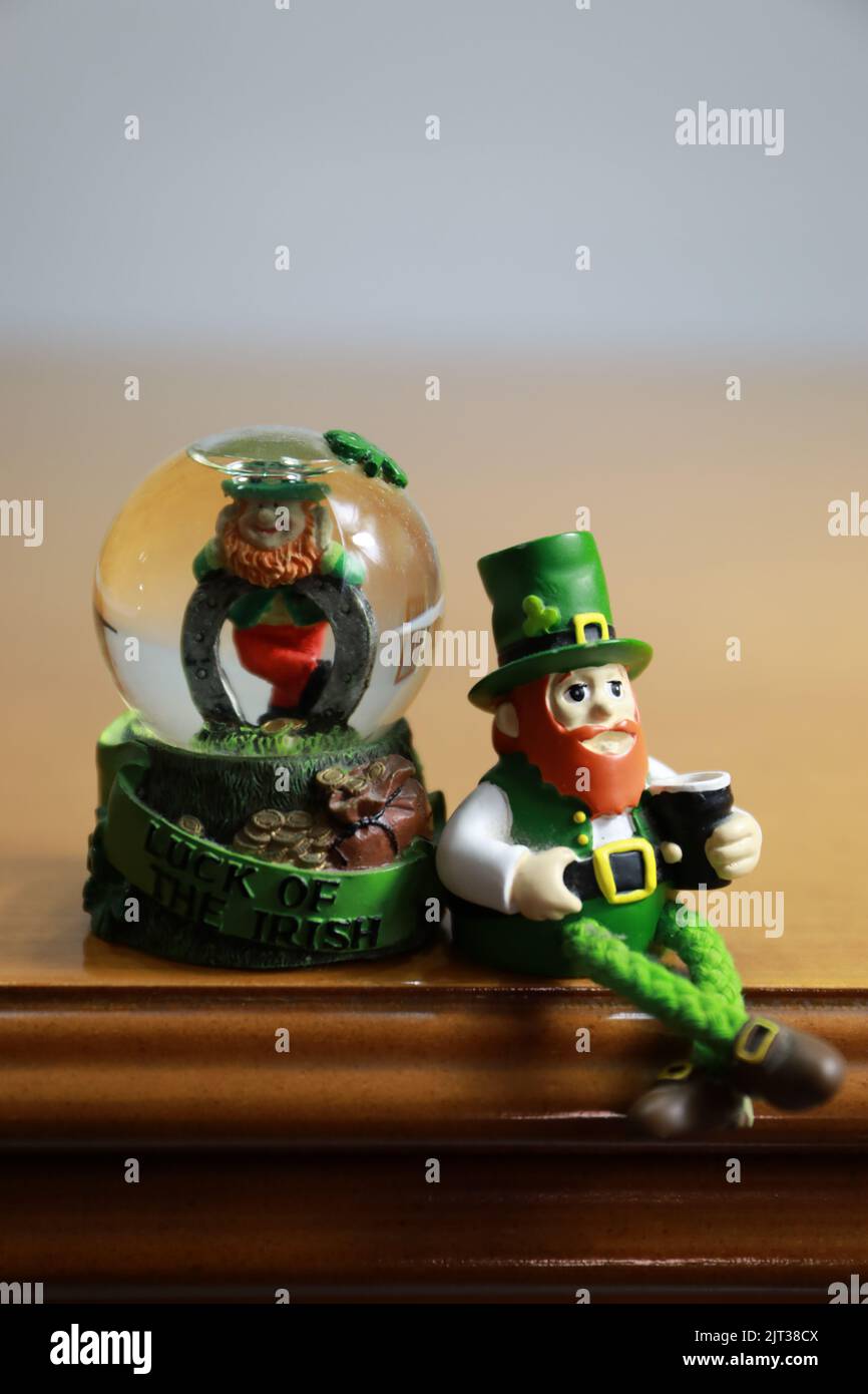A vertical closeup of leprechaun figurines isolated on the wooden furniture Stock Photo