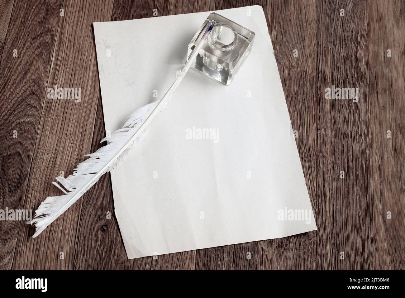 Vintage fountain pen with inkwell and empty sheet of paper on a wooden