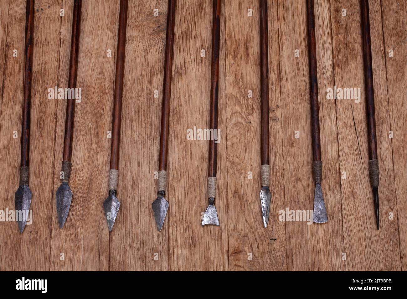Different types of arrowheads made of iron on wooden background Stock