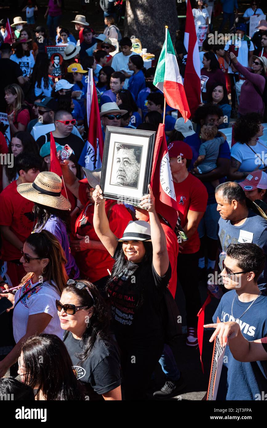 Photo of woman holding up a framed photo of UFW leader Cesar Chavez at the Sacramento capitol as part of an AB2183 farmworkers march. Stock Photo
