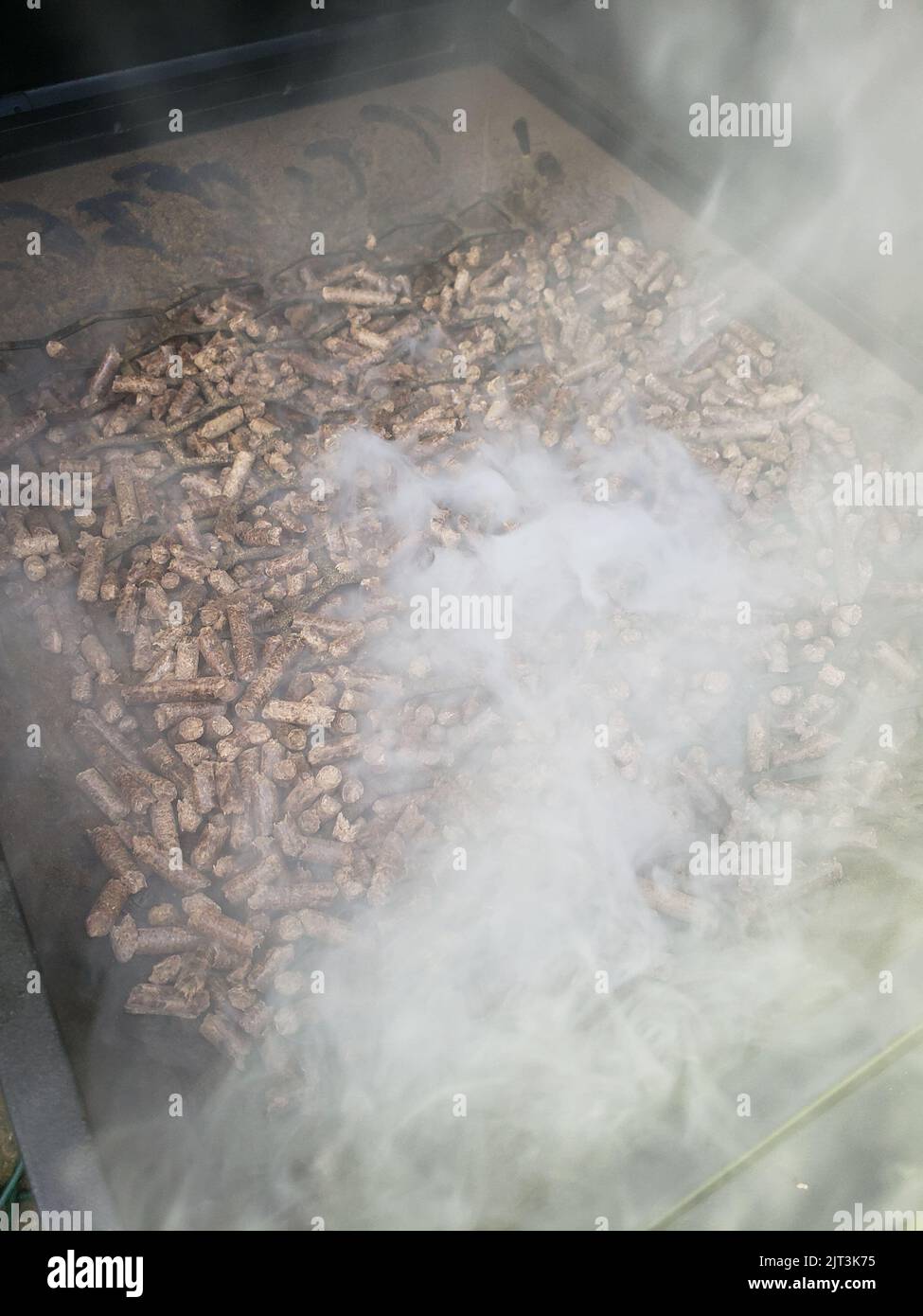 Pellets in a hopper of a smoker/grill with smoke flowing out Stock
