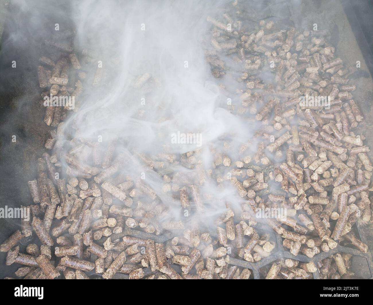 Pellets in a hopper of a smoker/grill with smoke flowing out Stock