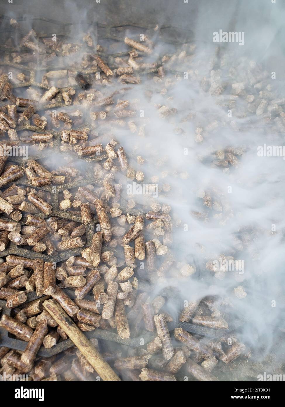 Pellets in a hopper of a smoker/grill with smoke flowing out Stock