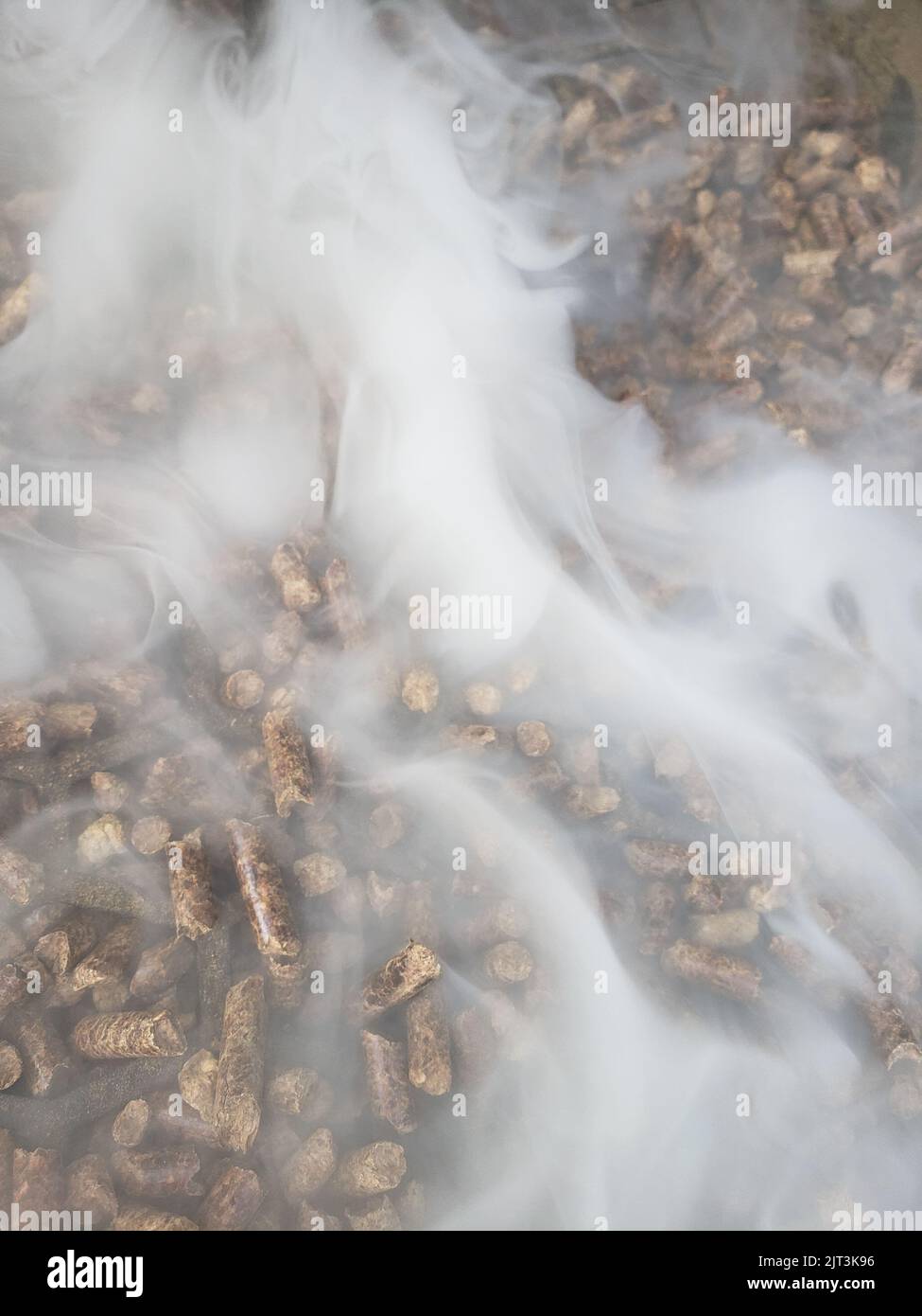 Pellets in a hopper of a smoker/grill with smoke flowing out Stock
