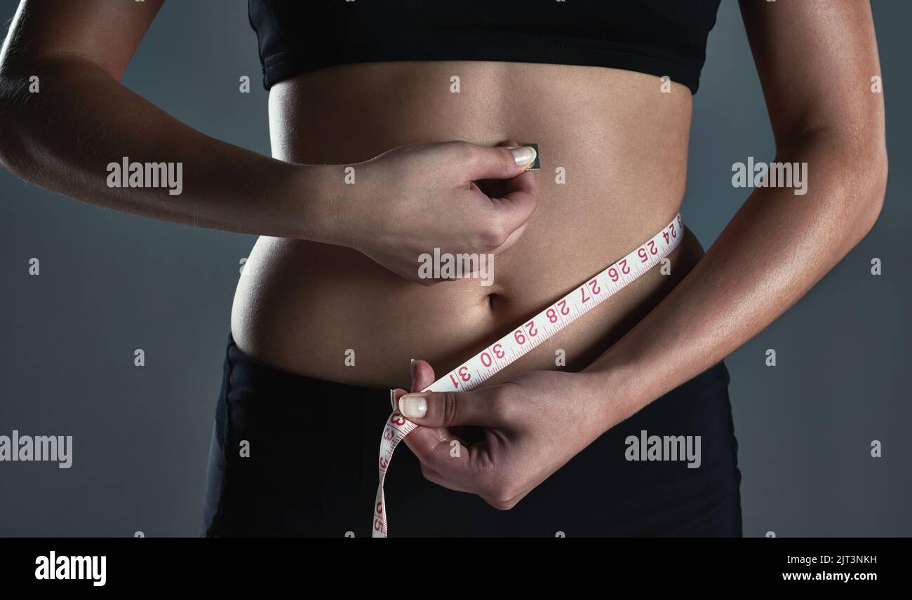 You get the body you work for. a sporty young woman measuring her waist. Stock Photo