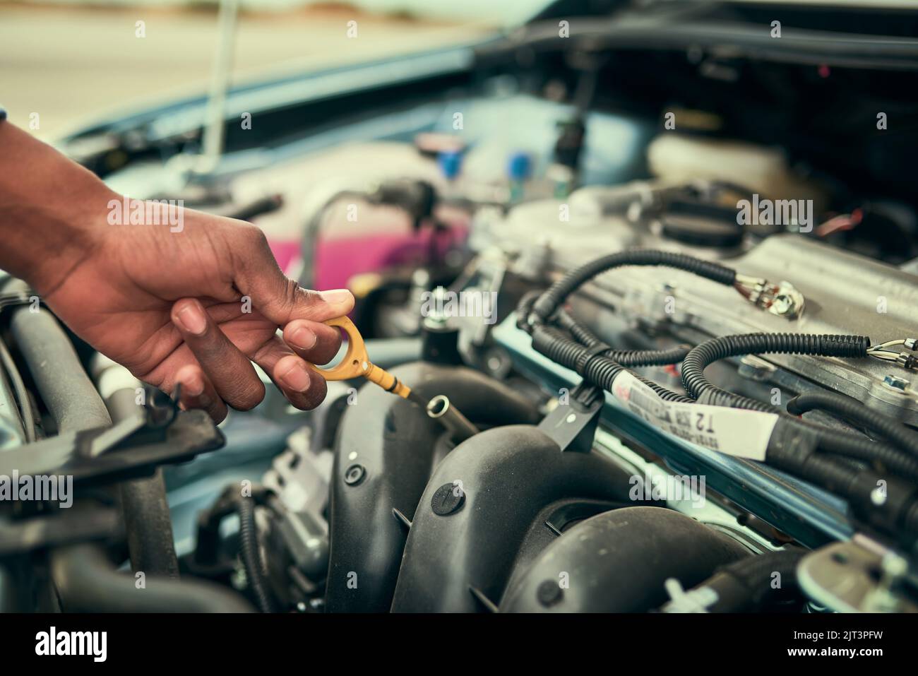 Checking his oil. a young man checking his engine oil after breaking down. Stock Photo