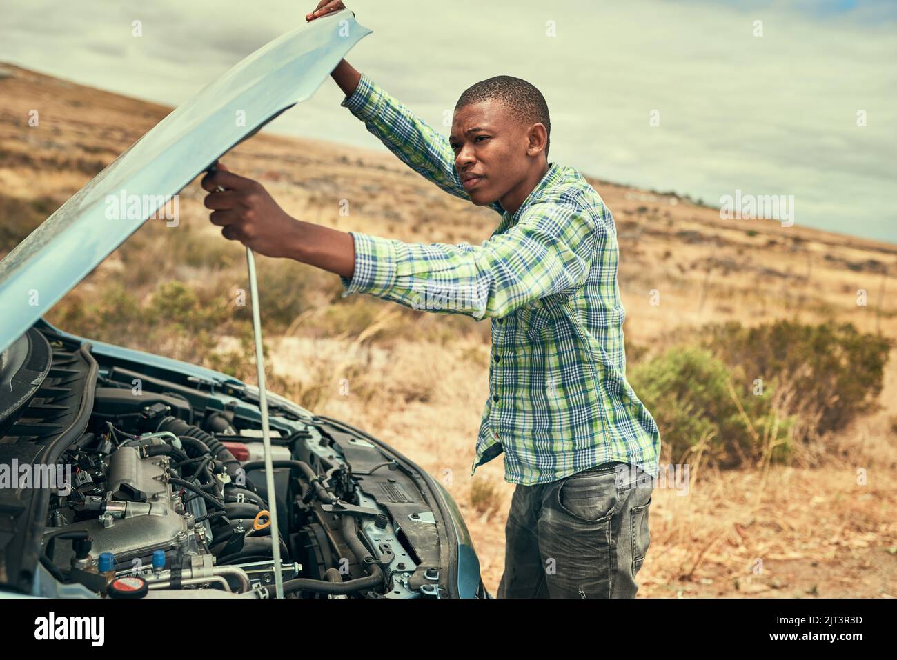 Pop the hood. a young man checking under the hood of his car after