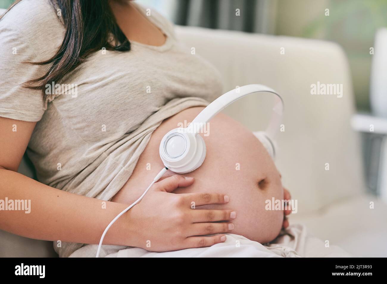 Music relaxes my baby. a woman wearing headphones over her pregnant belly Stock Photo Alamy