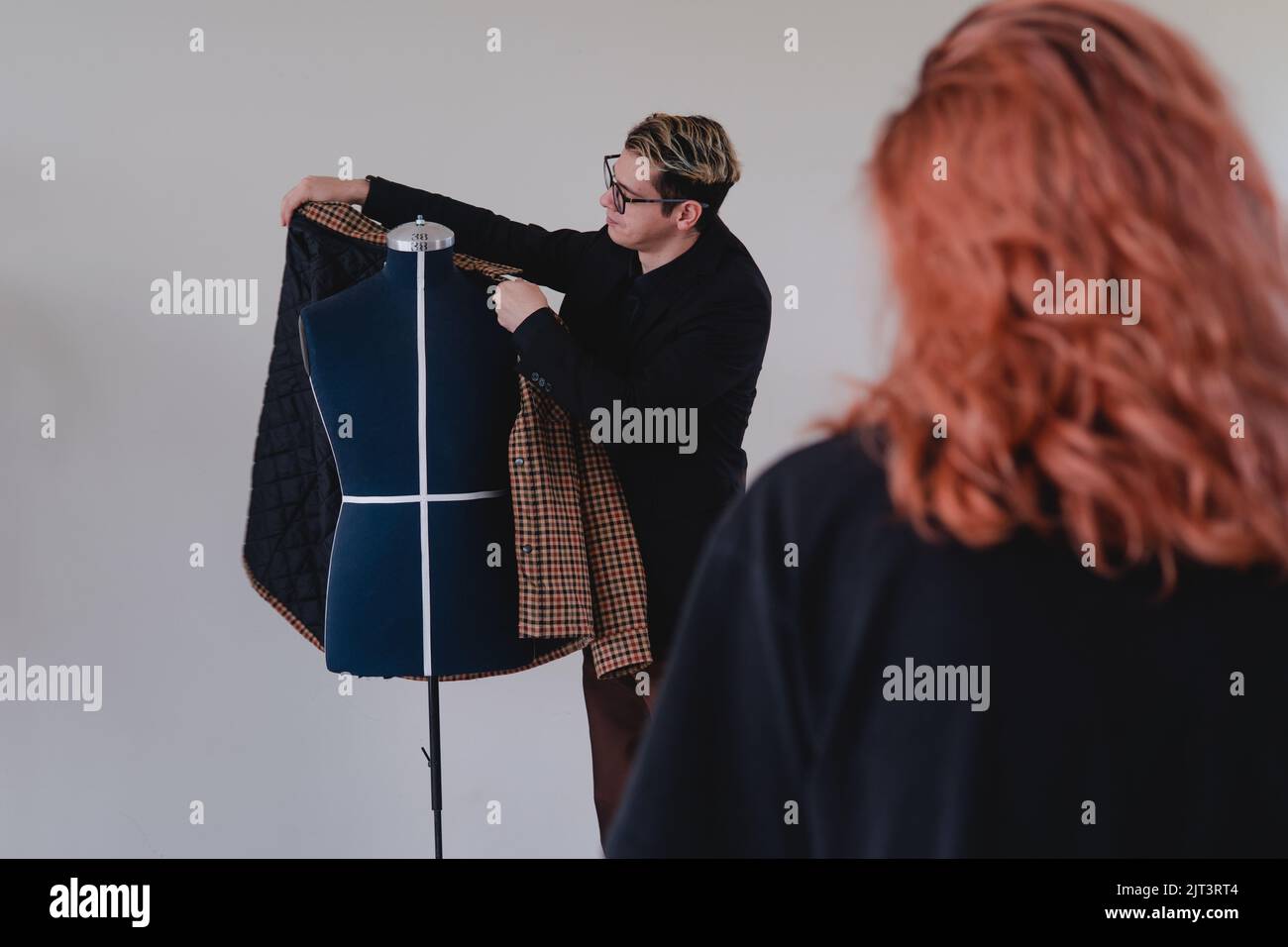 Tailor showing a suit to a female client. Tailor selling a suit. Fashion designer arranging a suit on a mannequin. High quality photo Stock Photo