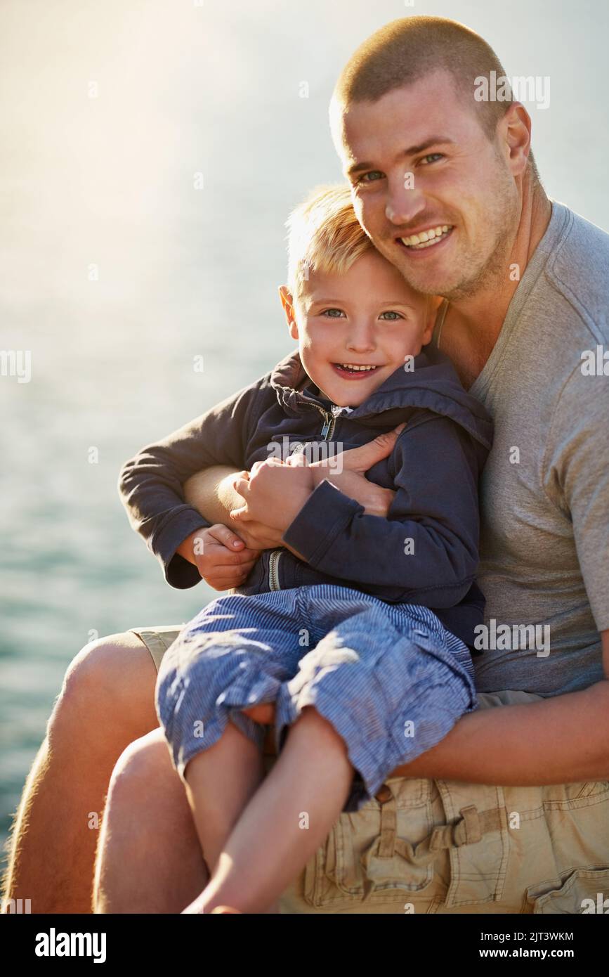 Every father is his sons first hero. Portrait of a father bonding with his little boy while they sit by the harbor. Stock Photo