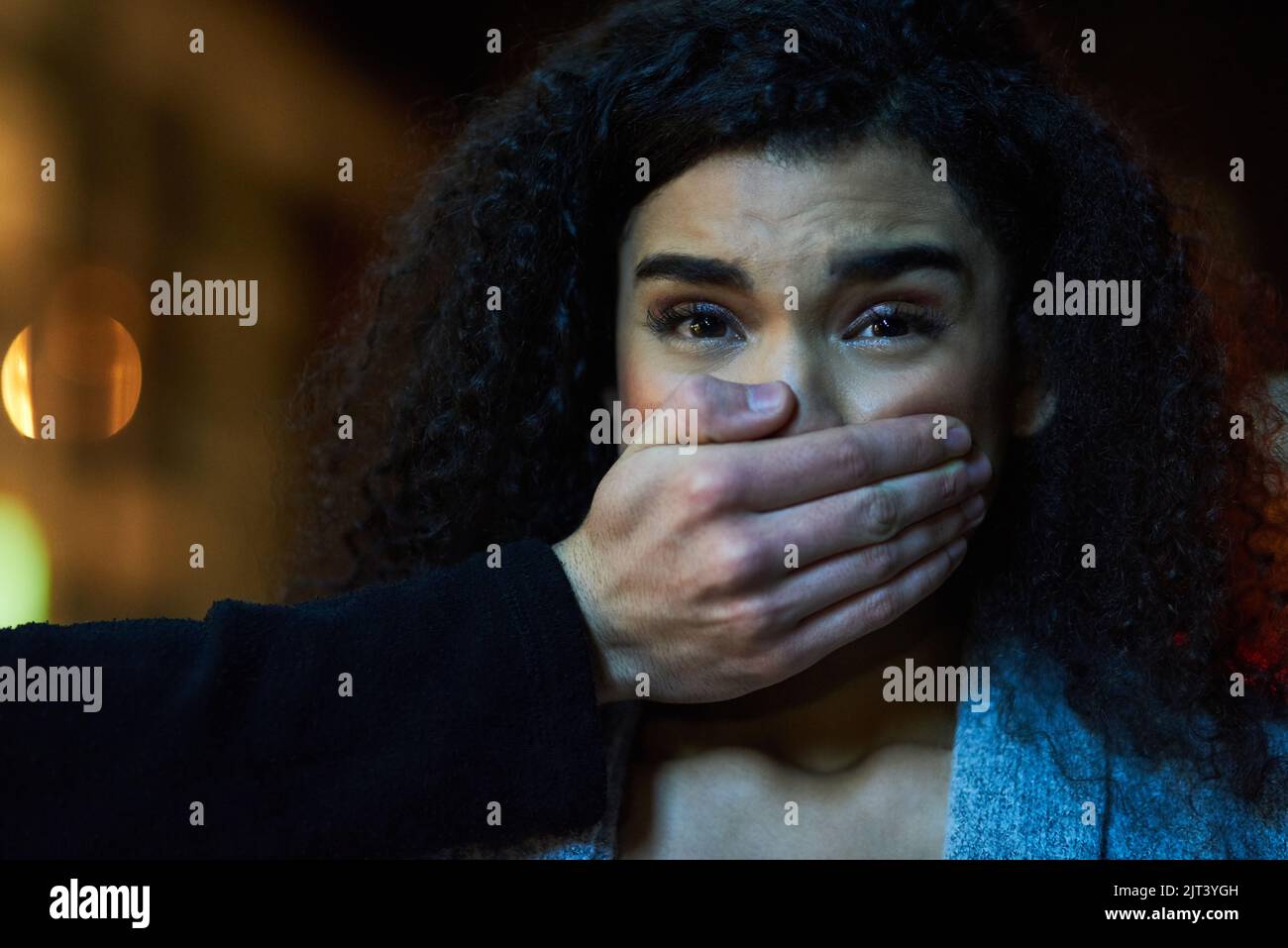 Its a moment that leaves you completely defenceless. Portrait of a frightened young woman with her assailants hand over her mouth. Stock Photo