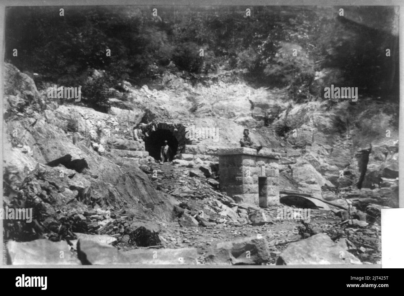 Tunnel in rock, with three men Stock Photo - Alamy