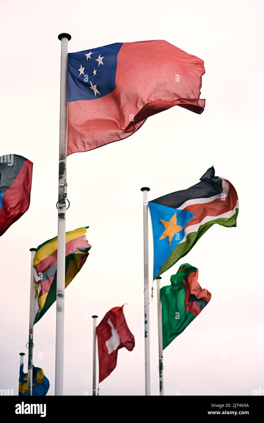 Representing many nations. the Samoan, Zimbabwean, Sudanese, Swiss and Swedish flags blowing in the wind. Stock Photo