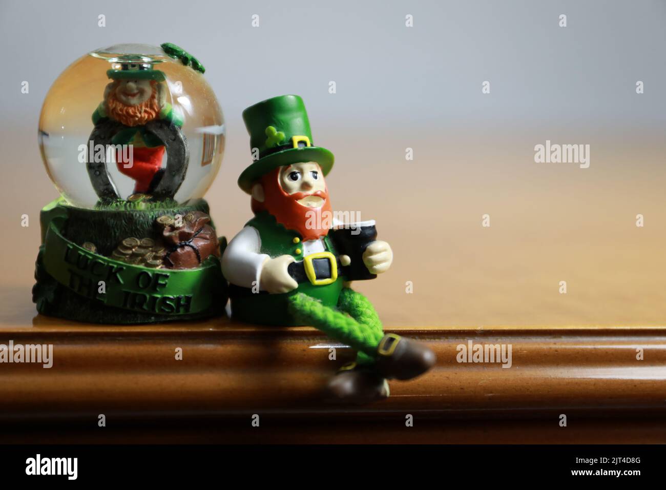 A closeup of leprechaun figurines isolated on the wooden furniture Stock Photo
