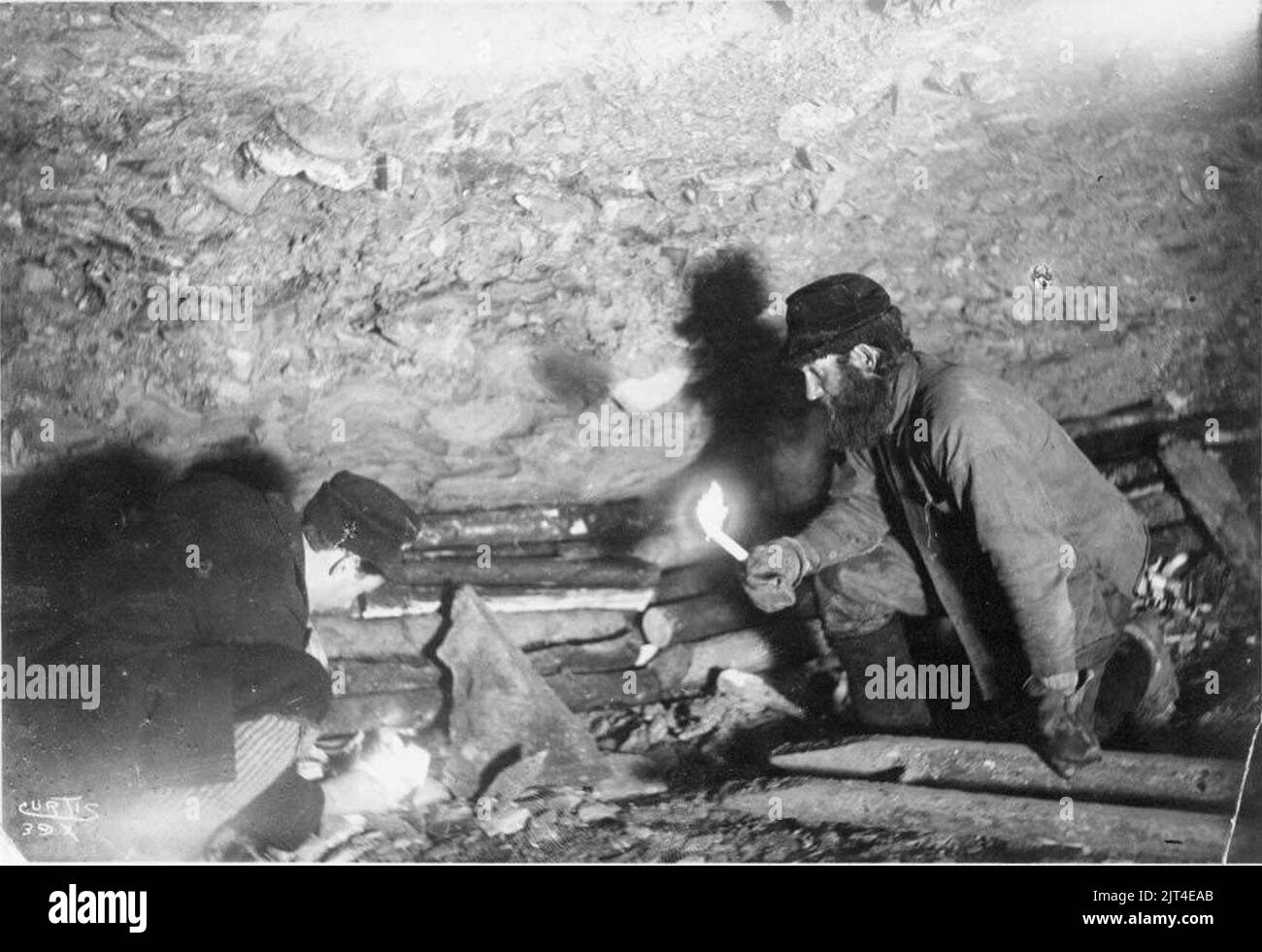 Two men, identified as Gorst and Ainsworth, building a fire in a mine