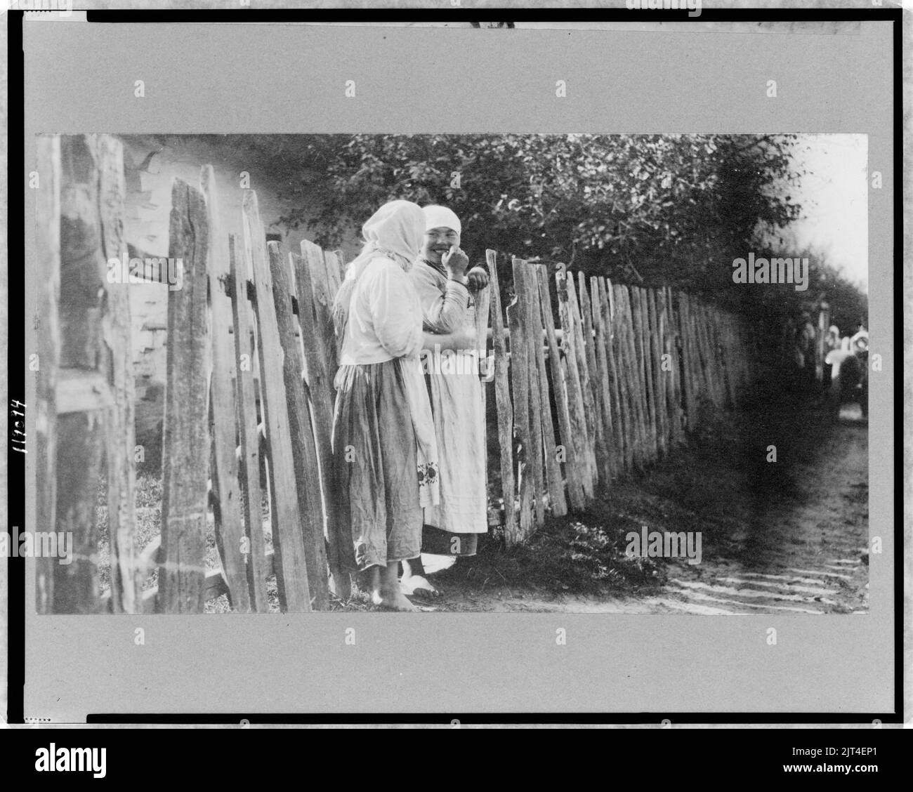Two peasant women standing along wooden fence, Russia Stock Photo