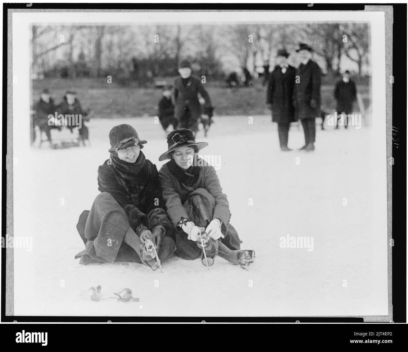 Two people seated on snow, and putting on ice skates, in the Washington, D.C., area Stock Photo
