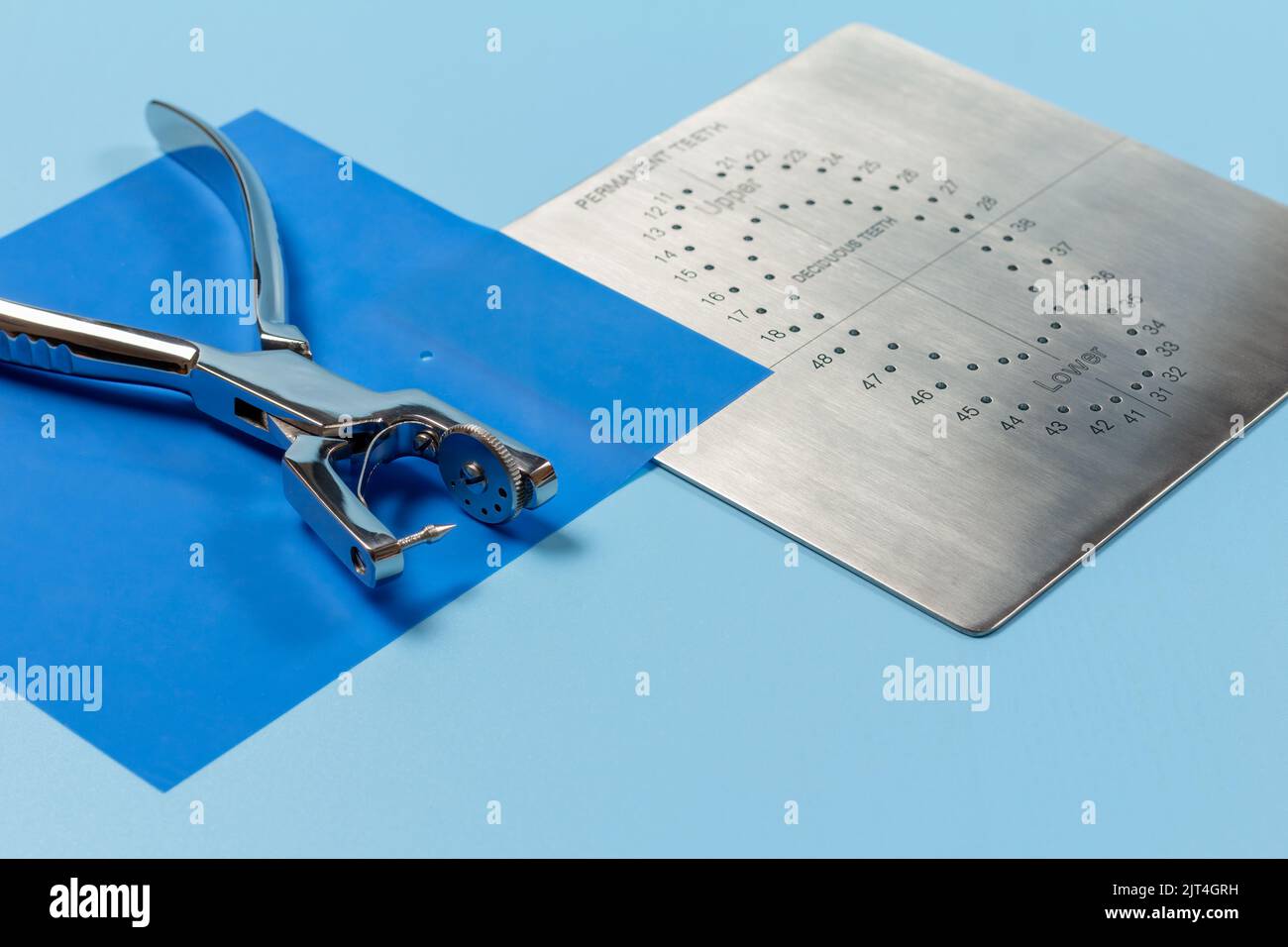 Dental hole punch, the rubber dam and the metal plate on the blue