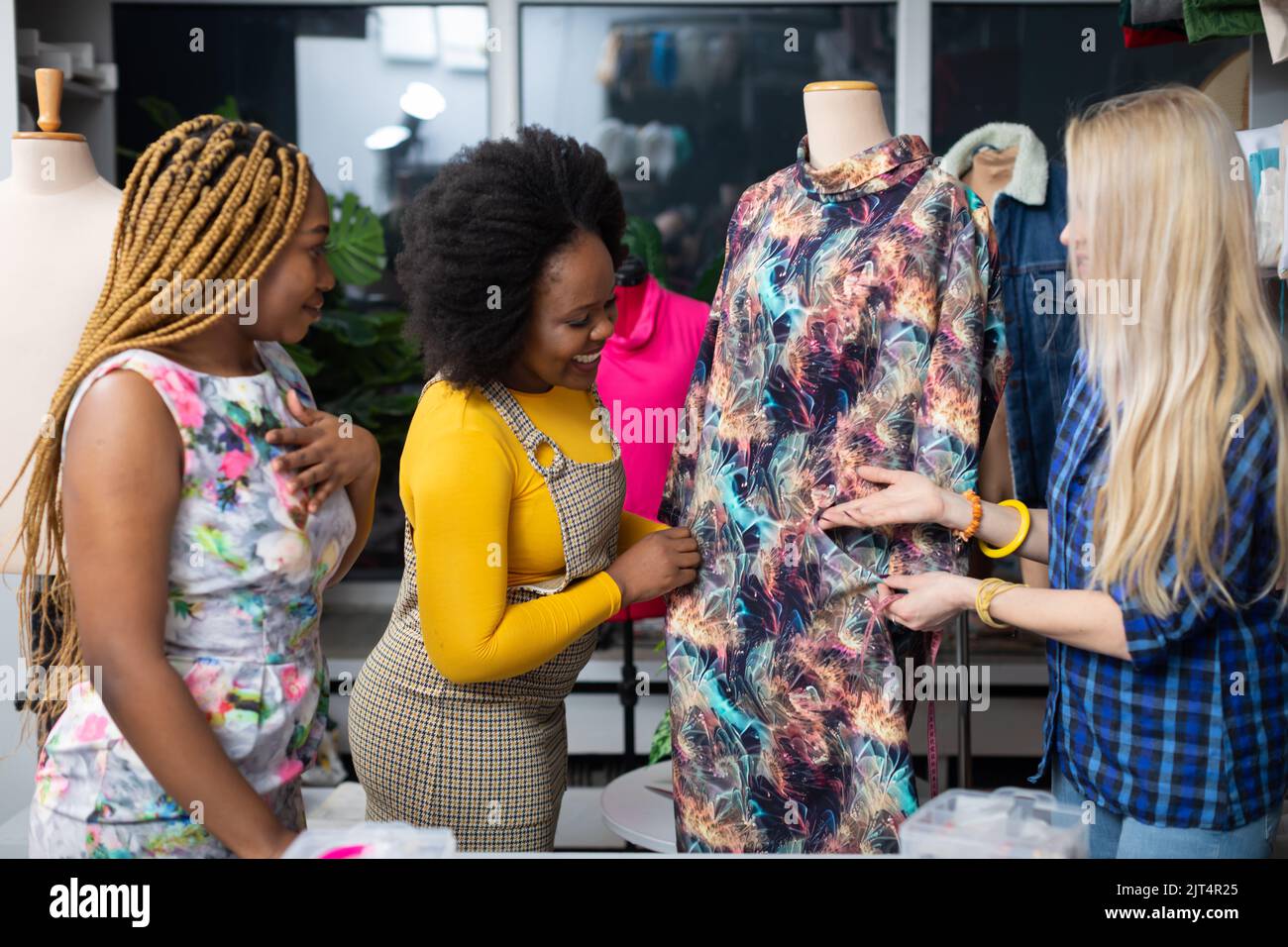 Two dark-skinned customers watch a dress in a tailor's shop. Stock Photo
