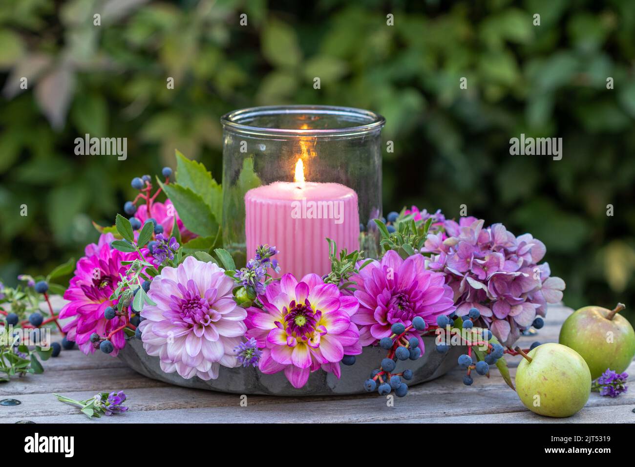 romantic arrangement with pink and purple dahlias and candle in garden Stock Photo