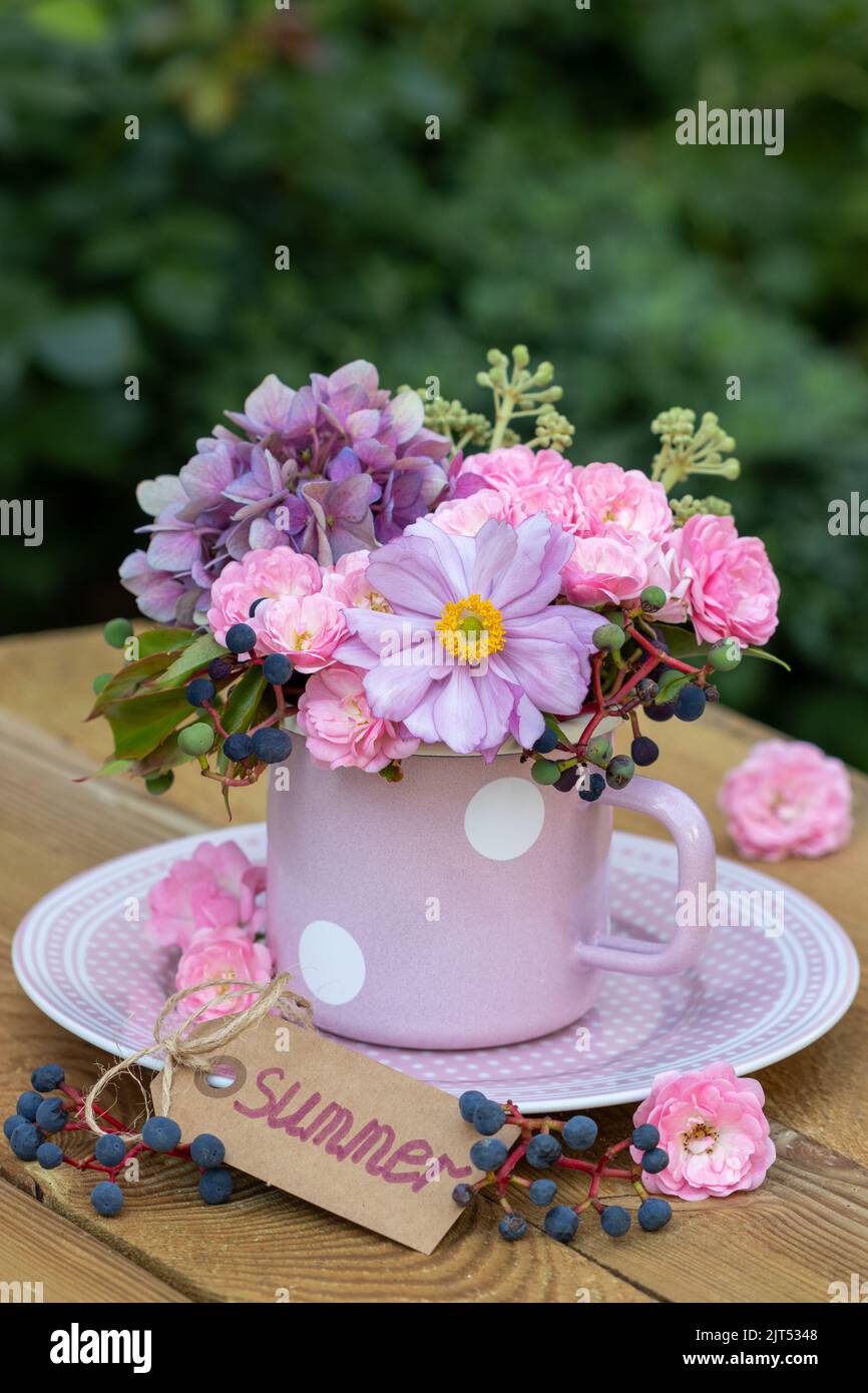 floral arrangement with anemone flower, pink roses and hydrangea flowers in enamel cup Stock Photo